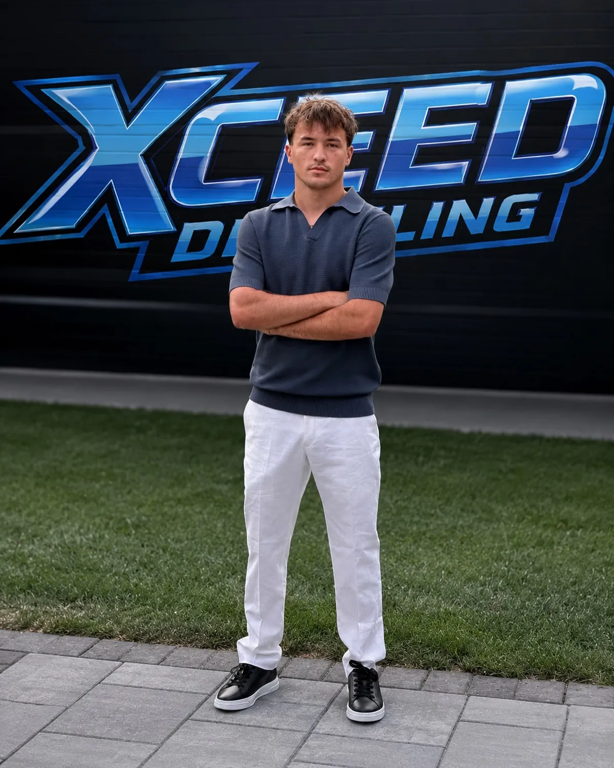 Cole, owner of Xceed Detailing, standing in front of the Xceed Detailing logo