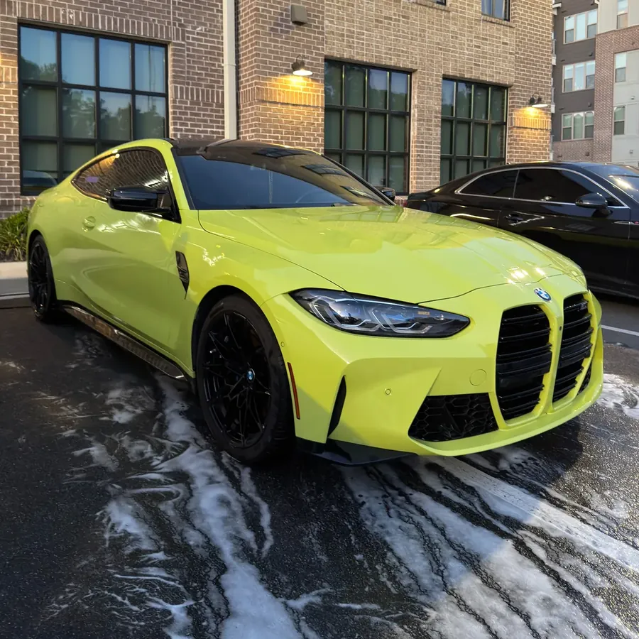 Lime green BMW M4 covered in foam during a wash